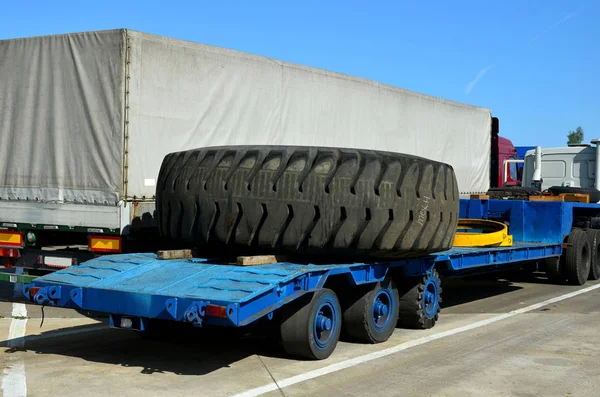 Transporting a large wheel for a mining truck on a truck trailer. The protector of a large rubber wheel. Rubber tire from the tipper  at an industrial plant for the production of cars.