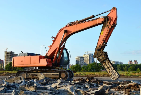 Crawler excavator with hydraulic hammer for the destruction of concrete and hard rock at the construction site. Replacing a concrete runway or road surface at an airport. Roadworks background - Image