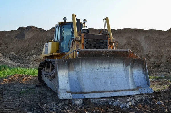 Bulldozer with bucket for pool excavation and utility trenching. Dozer during demolition concrete and asphalt at construction site. Earth-moving equipment for land clearing and foundation digging.