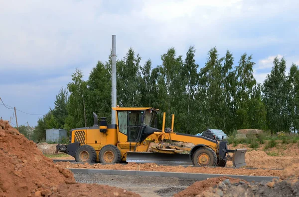 Onstruction machine Motor Grader at a construction site level the ground and gravel stones for the construction of a new asphalt road. Road construction equipment. — Stock Image Onstruction Machine Motor Grader Construction Site Level Ground Gravel Stones Royalty Free Stock Photos