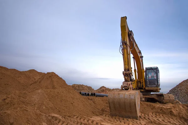 Excavator during construction of main water supply pipeline. Laying underground storm sewers at construction site. Water main sanitary drainage system for a multi-story buildings