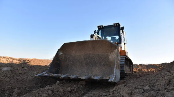 Crawler loader working on dirt at construction site. Earth-moving equipment for land clearing, grading, pool excavation, utility trenching and foundation digging. Tracked loader or dozer in quarry