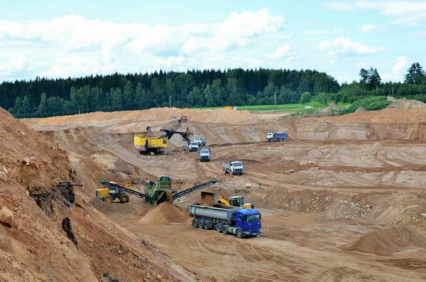 Wheel front-end loader loads sand into a dump truck. Heavy machinery in the mining quarry, excavators and trucks. Mobile jaw crusher plant with belt conveyor puts crushing and screening process