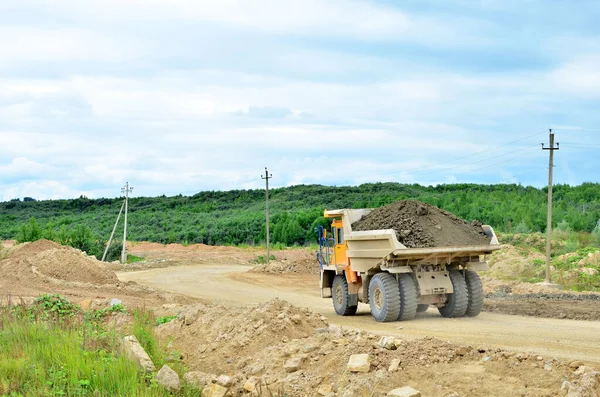 Big yellow mining truck working in the limestone open-pit. Loading and transportation of minerals in the dolomite mining quarry. Belarus, Vitebsk, in the largest dolomite deposit, quarry Gralevo