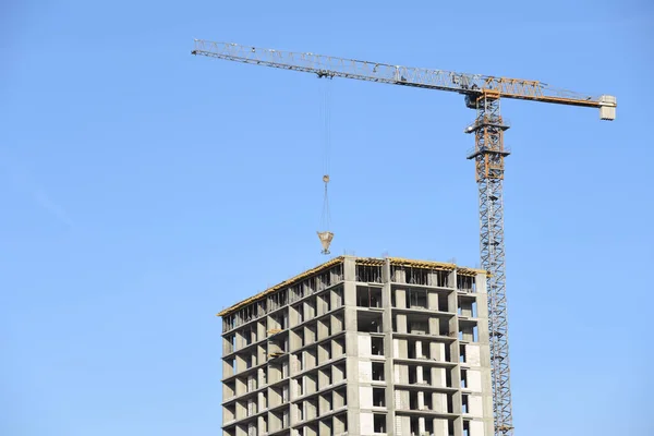 Tower cranes working at construction site against blue sky. Crane lifting a concrete bucket. Construction process of the new residential buildings. Transportation blocks and pouring of the cement mix