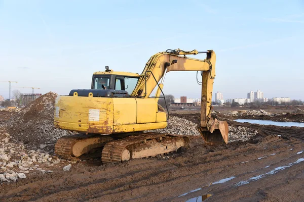 Yellow excavator during groundwork on construction site. Hydraulic backhoe on earthworks. Heavy equipment for demolition, construction and ground works. Digging foundation and laying storm sewer pipes