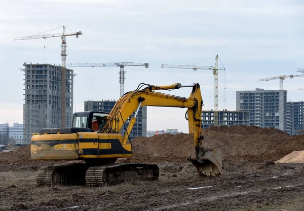 Yellow excavator during groundwork on construction site. Hydraulic backhoe on earthworks. Heavy equipment for demolition, construction and ground works. Digging foundation and laying storm sewer pipes