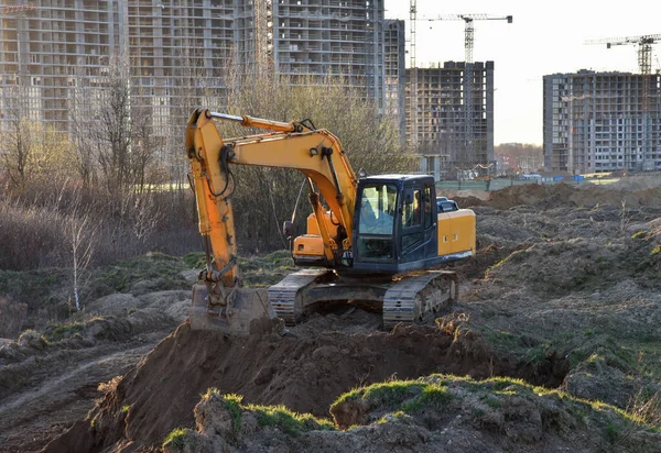 Excavator working at construction site on earthworks. Backhoe digging building foundatio. Construction machinery for excavating, loading, lifting and hauling of cargo
