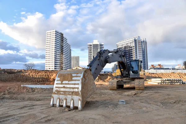 Construction of foundation excavator works in sand pit. Groundworks, site levelling, construction of reinforced ground beams on piled foundations at construction site. Earth-moving heavy equipment