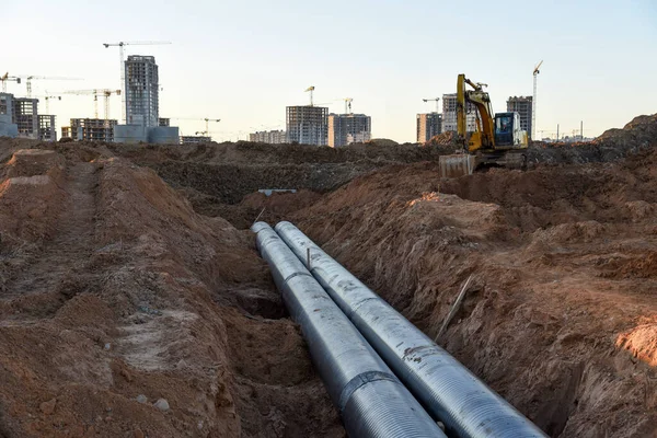 Excavator during construction of main water supply pipeline. Laying underground storm sewers at construction site. Water main sanitary drainage system for a multi-story buildings