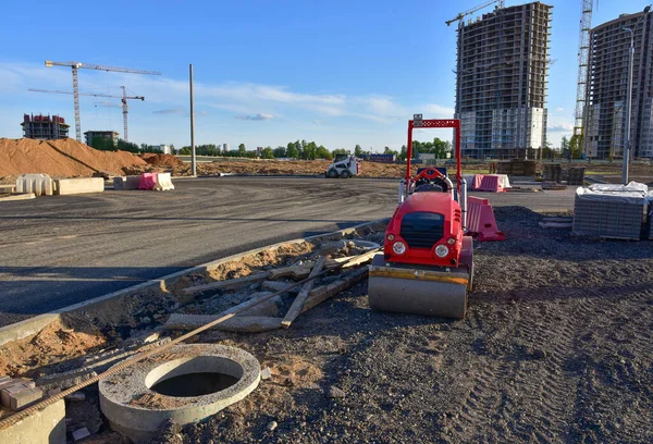 Paving roller machine during road work. Mini road roller at construction site for paving works. Screeding the sand for road concreting. Asphalt pavement is layered over concrete pavement