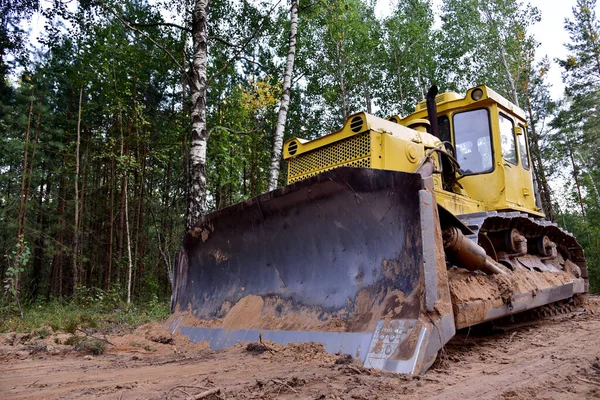 Dozer during clearing forest for construction new road . Yellow Bulldozer at forestry work Earth-moving equipment at road work, land clearing, grading, pool excavation, utility trenching