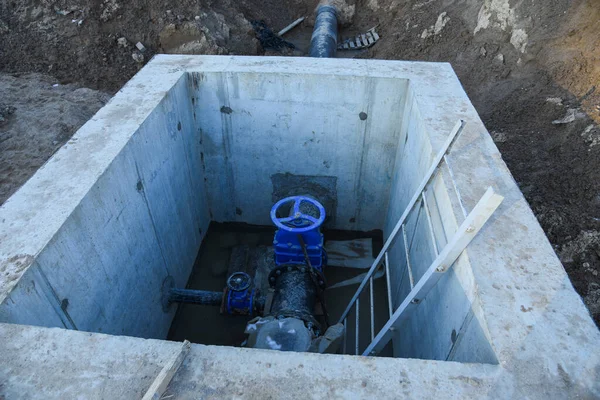 Resilient Seated Gate Valves connect pipeline of water supply in concrete bunker at constructin site. Solutions for drinking water and sewage. Valve pit of the system underground piping networks.