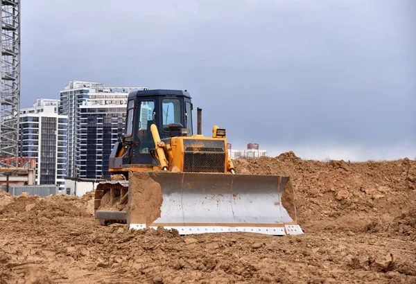 Dozer in action at construction site. Bulldozer for land clearing, demolition, pool excavation, utility trenching and foundation digging. Construction machinery and earth-moving equipment on dirt
