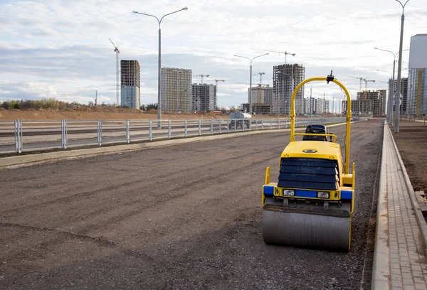 Paving roller machine during road work. Mini road roller at construction site for paving works. Screeding the sand for road concreting. Asphalt pavement is layered over concrete pavement