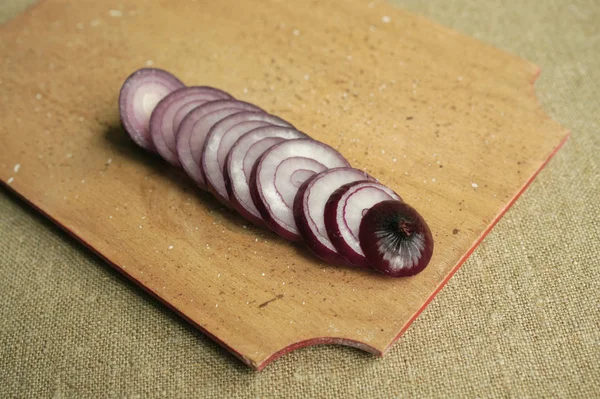 red onion sliced rings on a wooden board.