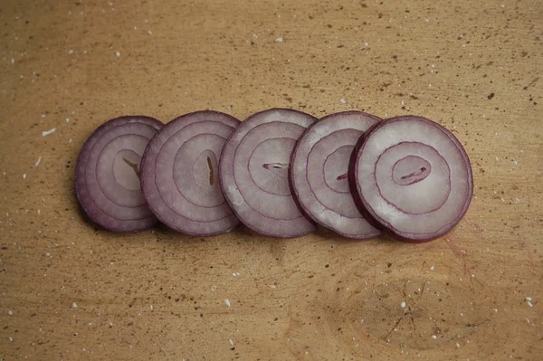 red onion sliced rings on a wooden board.