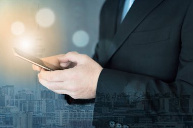 Cep telefonundan çalışan genç bir executive çift pozlama fotoğrafını. Şehir görünümü arka plan