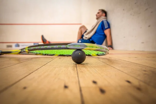 Çok sert bir squash oyunundan sonra yan duvara yaslayan bir adam.