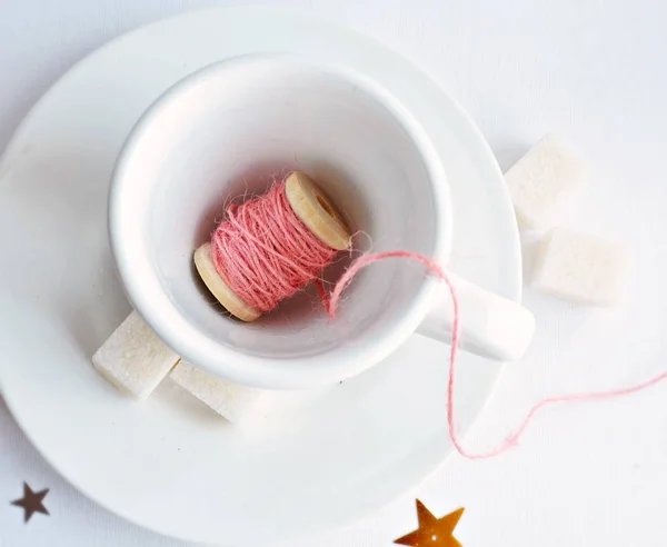 Pink jute string in white cup and sugar cubes