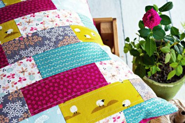 El yapımı patchwork yastık kılıfı ve yeşil tencerede sıcak pembe gül