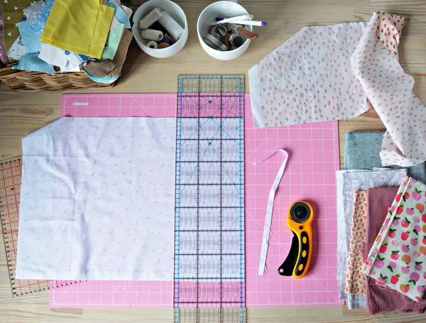 作業場所 綿織物 ピンクのカッティングマット キルティング定規 回転カッター 白いカップと木製の机の縫製用品 — ストック写真