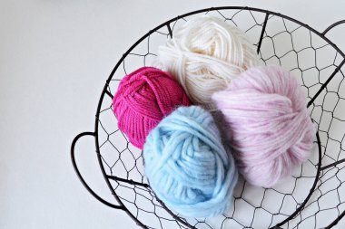 Yuvarlak tel sepette beyaz, mavi ve beyaz örgü iplik topları