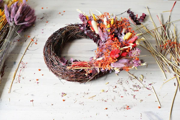 Festive fall wreath and colorful dried flowers on wooden desk