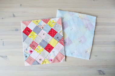 Ahşap masa üzerinde örtü iğneleri olan renkli bitmemiş yorgan.