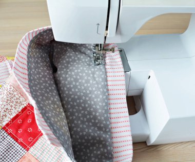 Çalışma süreci: ahşap masadaki kumaş ve dikiş makinesi 