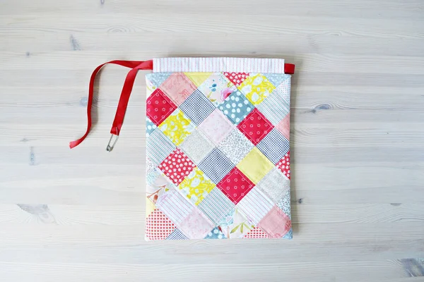 Renkli yama yaması çizgili çanta ve tahta masanın üzerinde emniyet pimi 