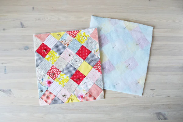 Ahşap masa üzerinde örtü iğneleri olan renkli bitmemiş yorgan.