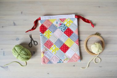 Renkli yama iplik torbası, yeşil ve sarı iplik, makas, ahşap masa üzerinde nakış halkası 