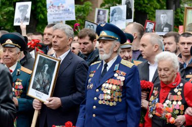 Kiev, Ukrayna - 9 Mayıs 2019: Kiev'deki Zafer Bayramı kutlamaları sırasında Ölümsüz Alayı yürüyüşüne katılan insanlar İkinci Dünya Savaşı askerlerinin fotoğraflarını tutuyor