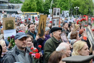 Kiev, Ukrayna - 9 Mayıs 2019: Kiev'deki Zafer Bayramı kutlamaları sırasında Ölümsüz Alayı yürüyüşüne katılan insanlar İkinci Dünya Savaşı askerlerinin fotoğraflarını tutuyor