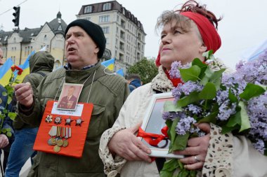Kiev, Ukrayna - 9 Mayıs 2019: Kiev'deki Zafer Bayramı kutlamaları sırasında Ölümsüz Alayı yürüyüşüne katılan insanlar İkinci Dünya Savaşı askerlerinin fotoğraflarını tutuyor