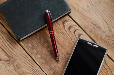 Kolu, telefon ve ahşap bir masa üstünde defter