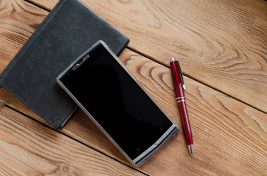 Kolu, telefon ve ahşap bir masa üstünde defter