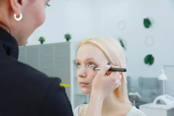 Процесс нанесения макияжа девушки визажиста — стоковое фото