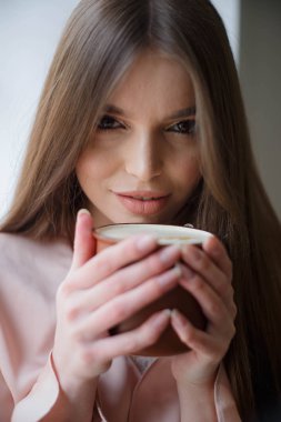 Güzel kız kahve içme ve kafede otururken gülümseyen