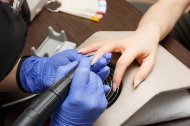 Closeup çekim bir manikür elektrik törpü ile bir güzellik uzmanı tarafından alma bir tırnak salonu içinde bir kadın. Kadın Başlarken tırnak manikür. Şevval Özçelik Güzellik dosya bir müşteriye çivi