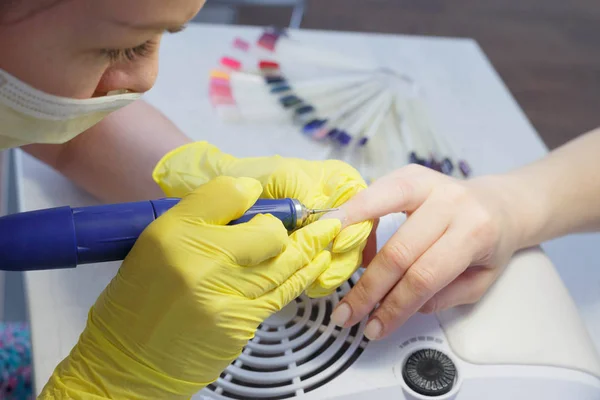 The girl in the salon nail service. Alignment of nails and treat