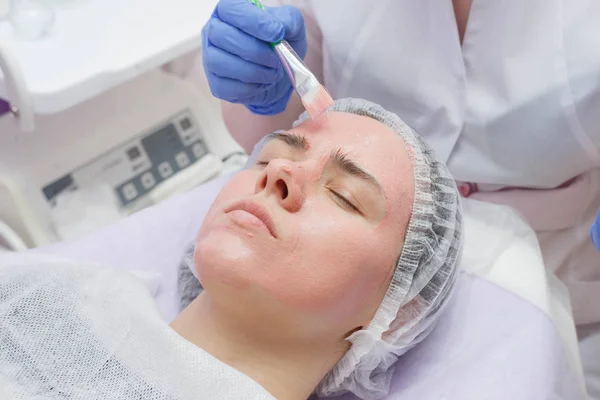 Meester creëert een masker op het gezicht van een jong meisje. — Stockfoto