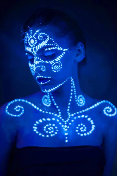 Body art on the body and hand of a girl glowing in the ultraviolet light.