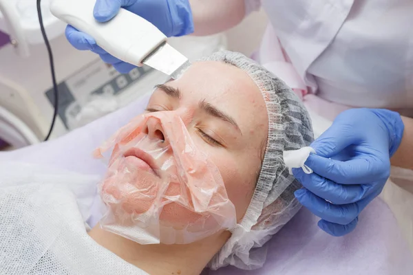 The girl is provided with an ultrasound skin cleaning service in the beauty salon.