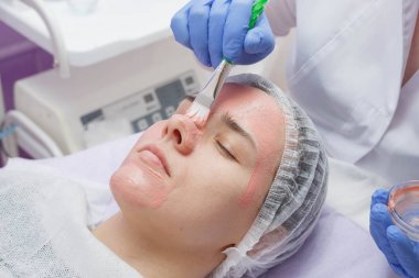 Usta genç bir kızın yüzünde bir maske oluşturur.