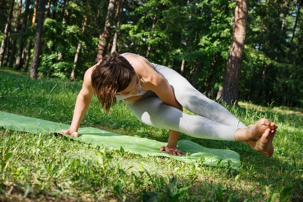 Das Mädchen praktiziert an einem sonnigen Tag Yoga im Park. — Stockfoto