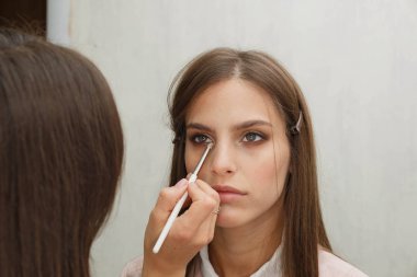 Makyaj yapma süreci. Modelin yüzünde bir fırça ile çalışan makyaj sanatçısı.