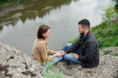 Bir erkek ve bir kadın taş bir platformda yüz yüze oturuyorlar..