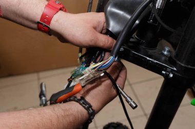 Yeni bir motosikletin montajında elektrik tellerinin bağlanması işlemi.